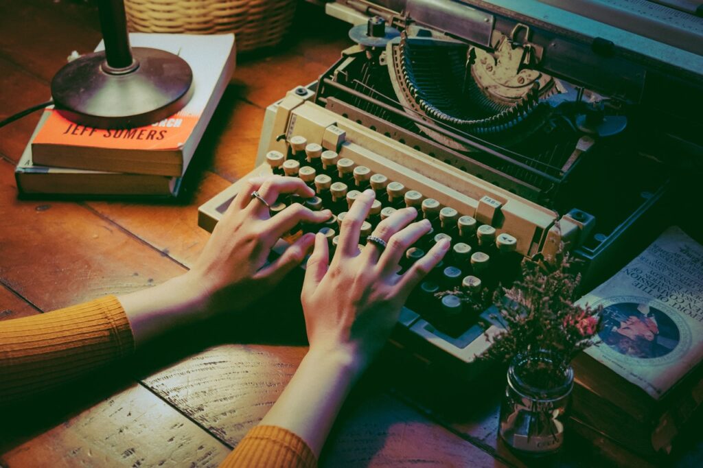 writing at a typewriter, writer, pain, choosing our pain, Kristen Lamb