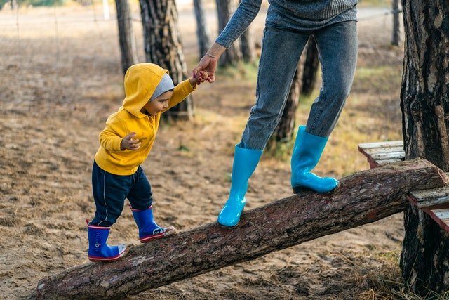 woman helping little boy walk on a log, weakness