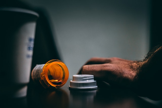 man's hand near a bottle of pills